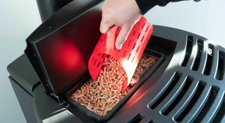Main d'une personne versant des granulés de bois dans un poêle Palazzetti. Réglage de l'alimentation pour un fonctionnement optimal.