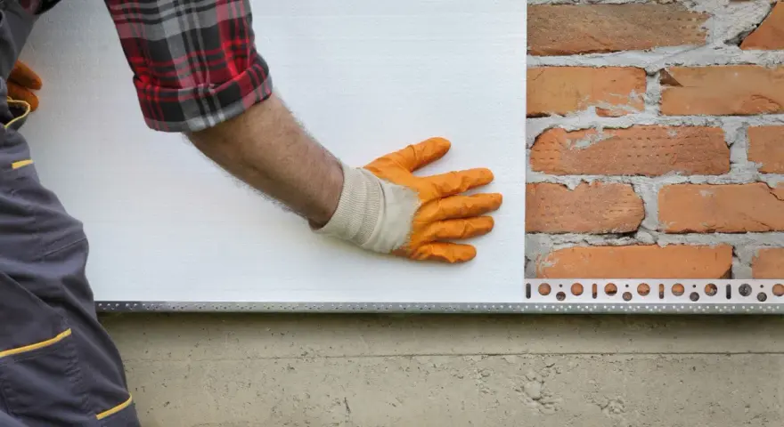 Pose d'isolant blanc sur mur de briques. Estimation du prix isolation extérieur maison 140m2.