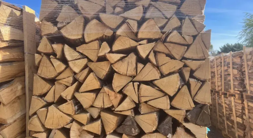 Un grand stère de bois, bien empilé et emballé sous plastique, prêt pour l'hiver.