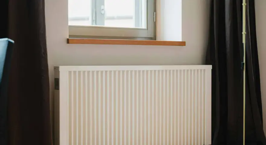 Radiateur électrique blanc sous une fenêtre, prêt pour un changement grâce à l'aide de l'état.