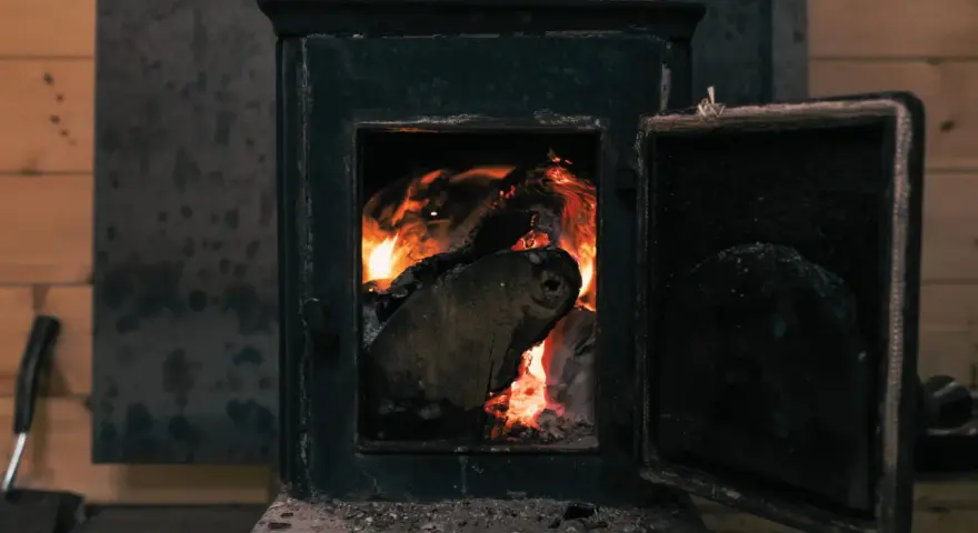 Poêle à bois avec porte ouverte et flammes vives dans le foyer.