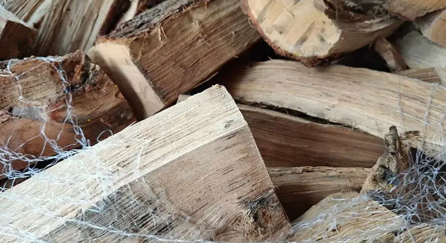 Gros plan sur un poids stère de bois sec, emballé dans un filet blanc, prêt pour l'hiver.