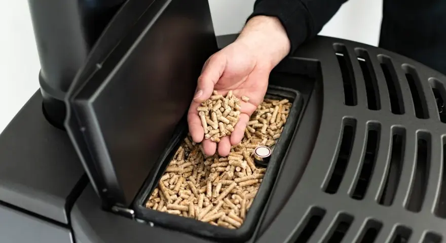 Main d'homme versant des granulés de bois dans un poêle, signalant une alarme manque pellet.