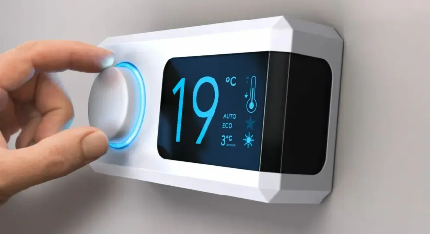 Main d'une personne ajustant le réglage de température sur un cee thermostat connecté affichant 19°C.