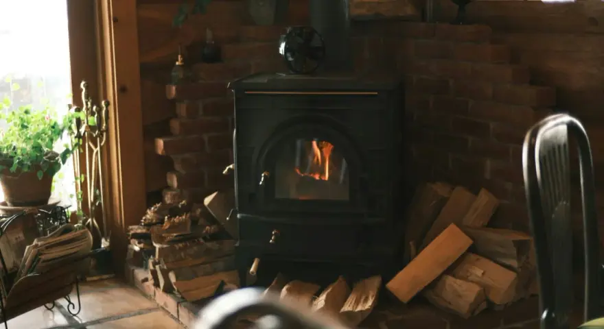 Poêle à bois avec arrivée d'air extérieur, crépitant joyeusement dans un coin cosy, entouré de bois prêt à chauffer.