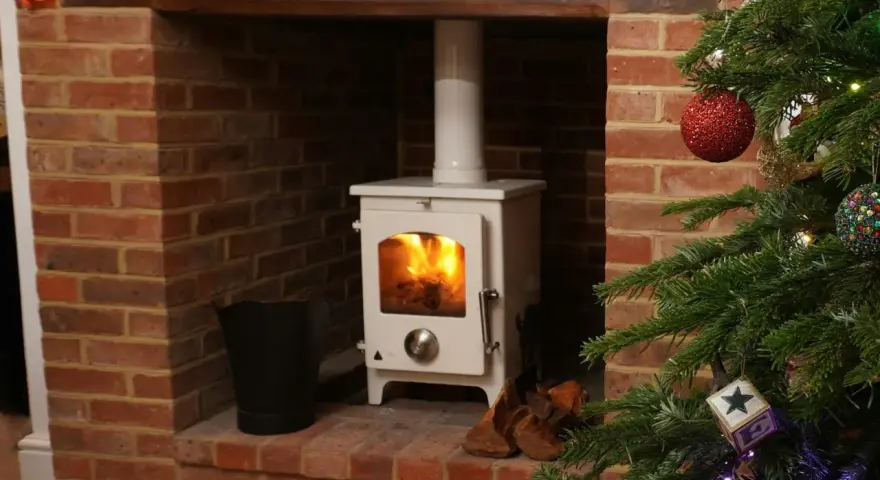 Installation d'un poêle à granulés avec conduit existant dans une cheminée en briques, décorée pour Noël.