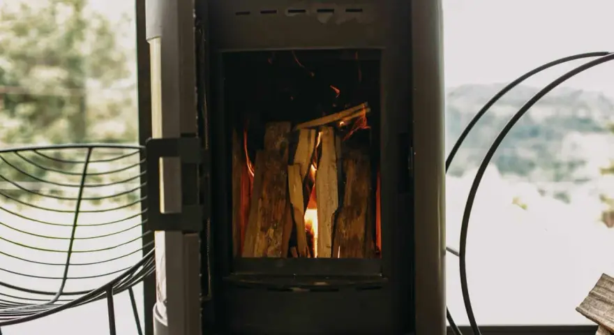 Poêle à bois allumé, avec une prise d'air poele à bois obligatoire pour une combustion optimale. Le feu crépite joyeusement.