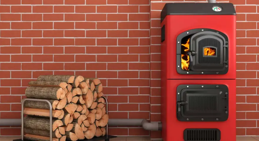 Une chaudière biomasse rouge flamboyante, avec une porte ouverte révélant des flammes vives, est prête à chauffer une maison. À côté, une pile de bois de chauffage attend patiemment.
