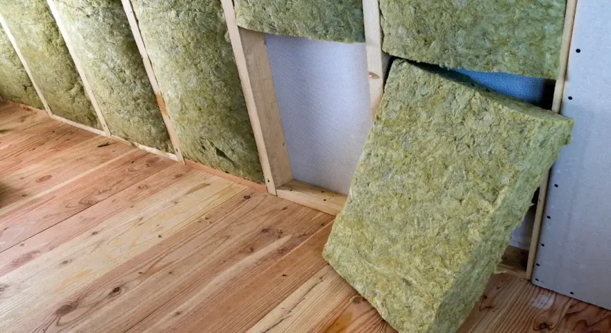 Isolation d'un grenier avec de la laine de verre sans pare vapeur, posée entre les chevrons sur un plancher en bois.
