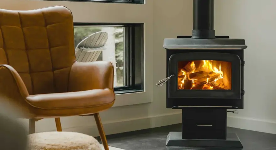 Un confortable fauteuil en cuir brun fait face à un poêle à bois non étanche, où des flammes dansent joyeusement dans le foyer.