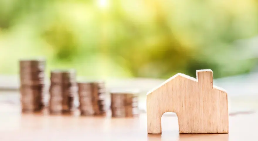 Une petite maison en bois et des piles de pièces de monnaie suggèrent un coup de pouce pour quel groupe : les investisseurs immobiliers.