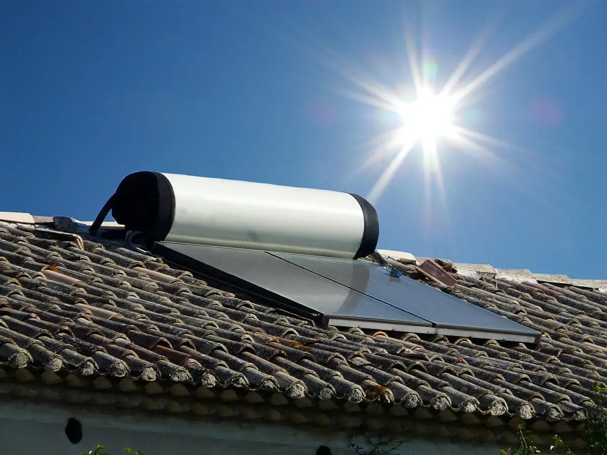 Un chauffe-eau solaire sur un toit de tuiles, sous un soleil éclatant. L'énergie solaire pour chauffer l'eau.