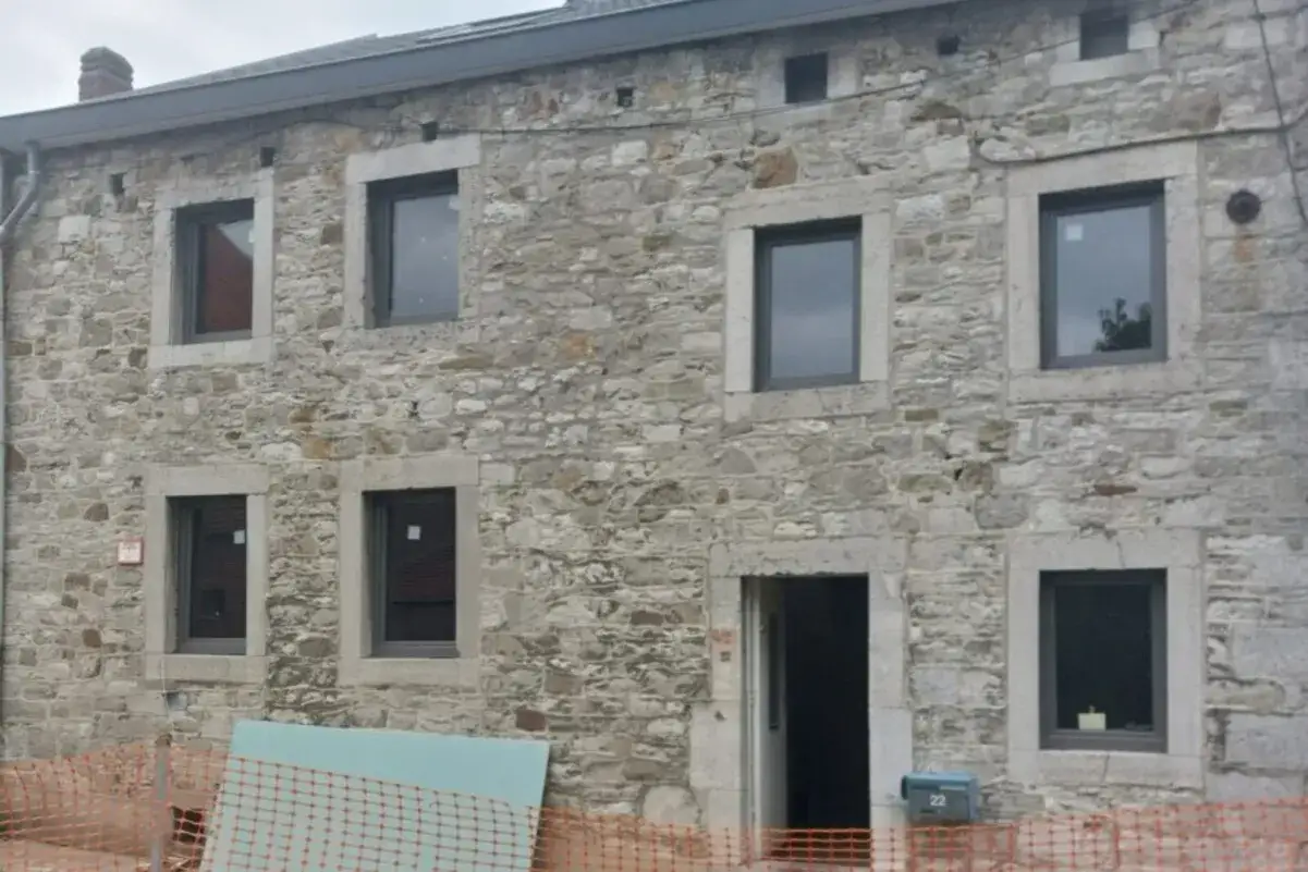 Façade en pierre d'une maison ancienne en rénovation, avec de nouvelles fenêtres et des matériaux pour l'isolation mur intérieur.