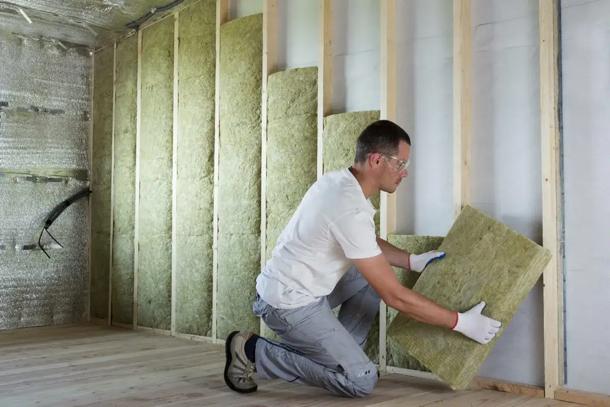 Un ouvrier installe un panneau d'isolation min&eacute;rale pour l'isolation mur int&eacute;rieur d'une maison en construction.