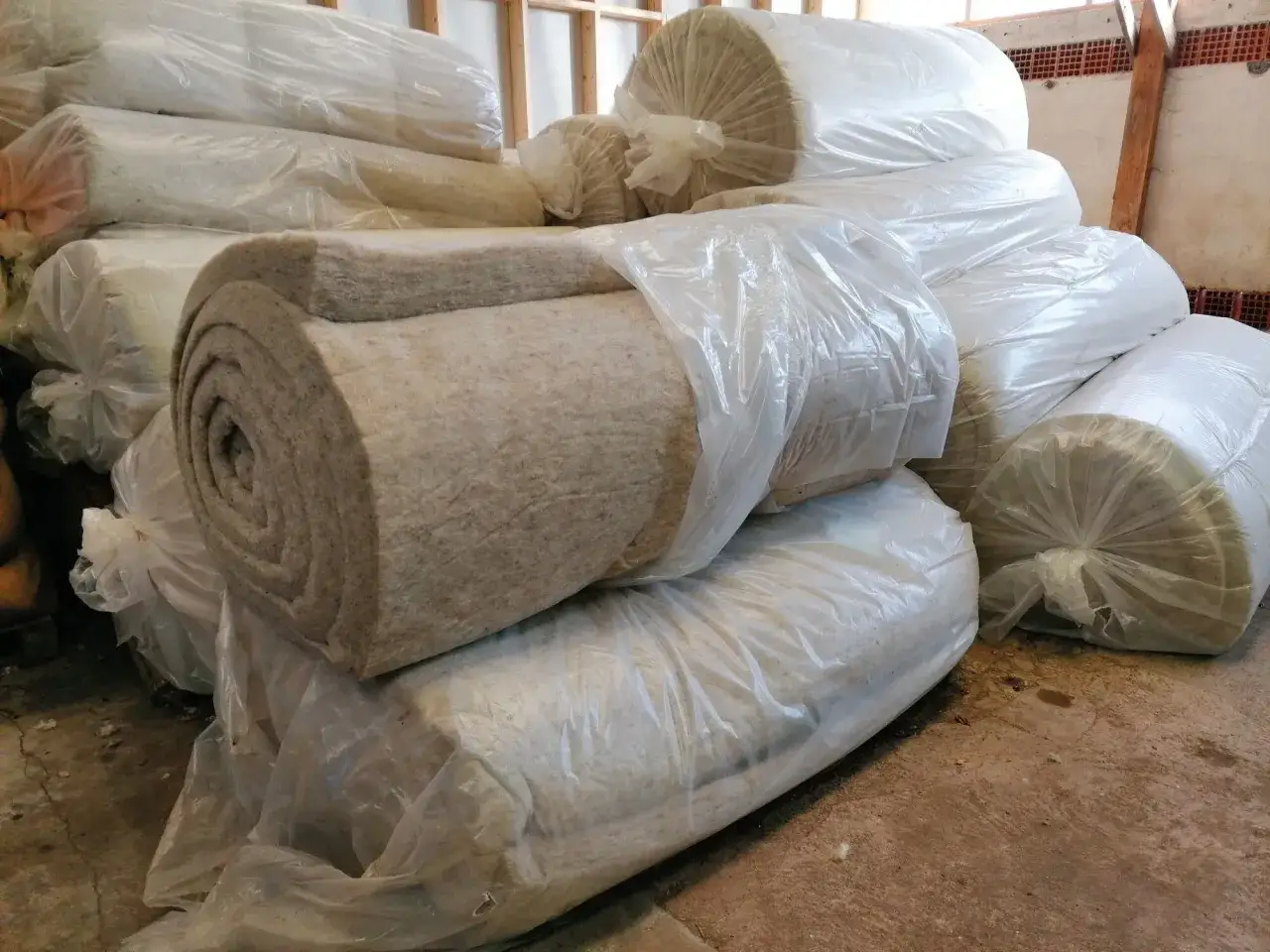 Rouleaux de laine de mouton pour isolation, empilés et emballés dans du plastique.