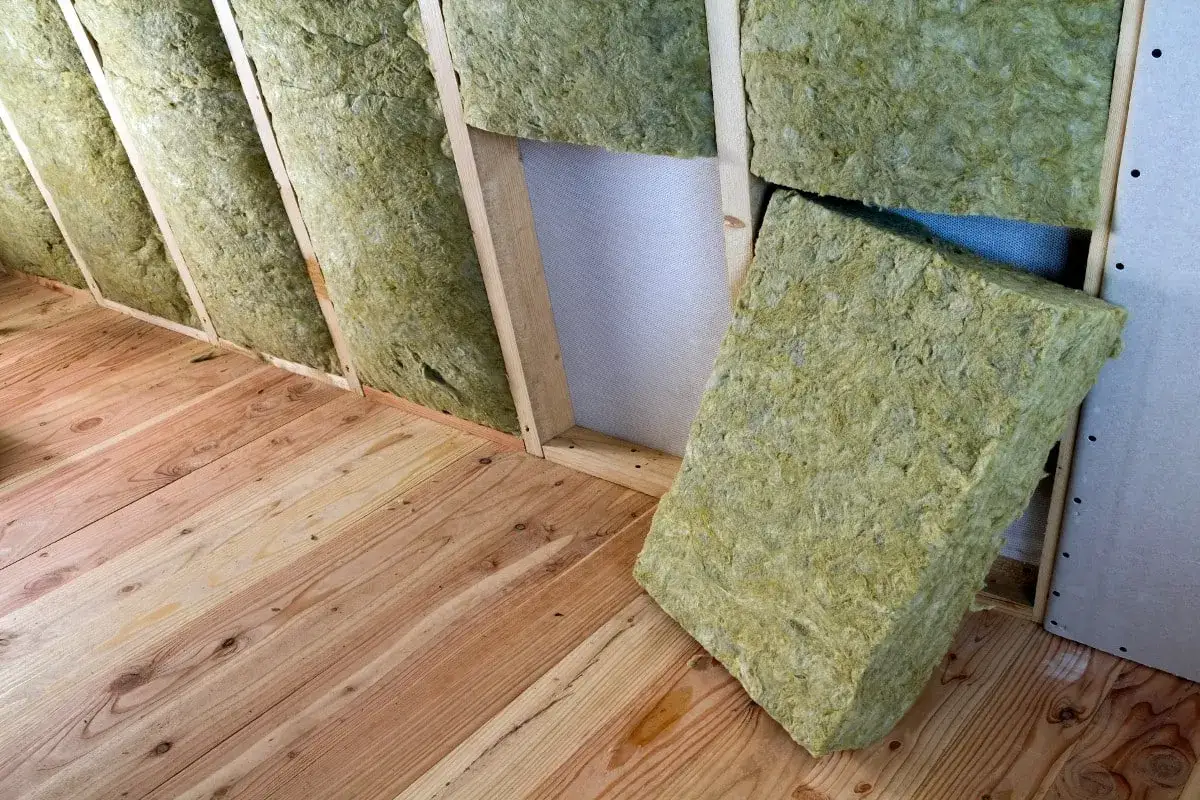 Isolation d'un grenier avec de la laine de verre sans pare-vapeur, posée sur un plancher en bois brut.