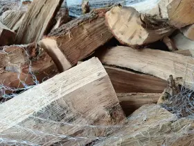 Gros plan sur un poids stère de bois sec, emballé dans un filet blanc, prêt pour l'hiver.