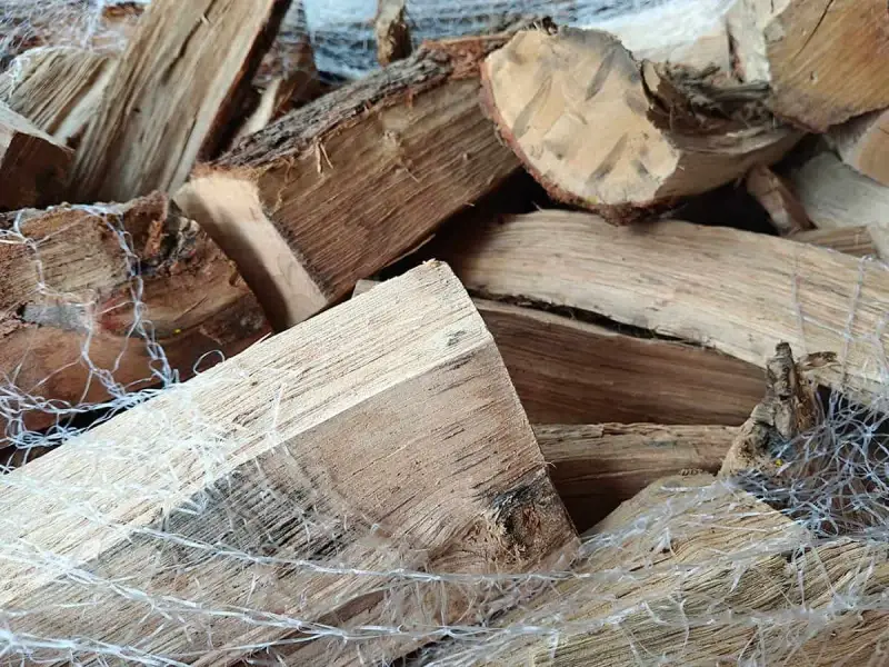Gros plan sur un poids stère de bois sec, emballé dans un filet blanc, prêt pour l'hiver.