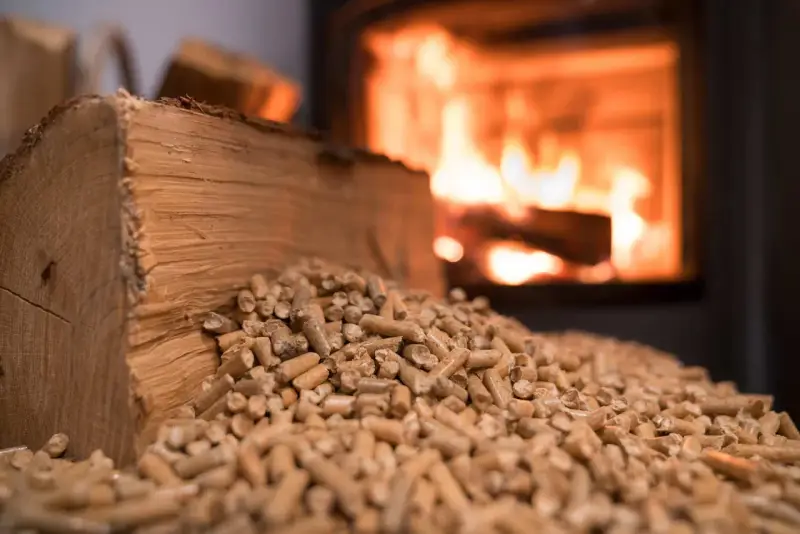 Bûches et granulés de bois, prêts pour une chaudière bois mixte. Le feu crépite en arrière-plan.